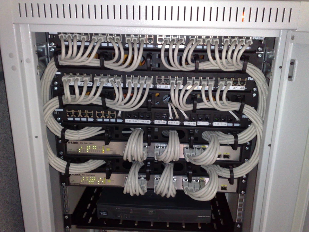 Conmutadores D-Link y paneles de conexión unidos por cables de red en un rack.