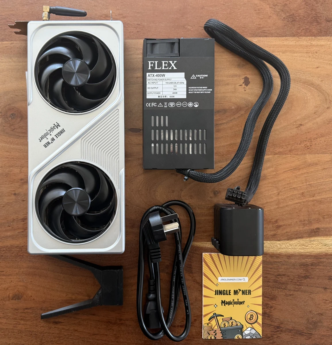 Contextual product photo of a Jingle Miner BTC Hashcard, power supply and cables; not a LuxOS compatibility claim.